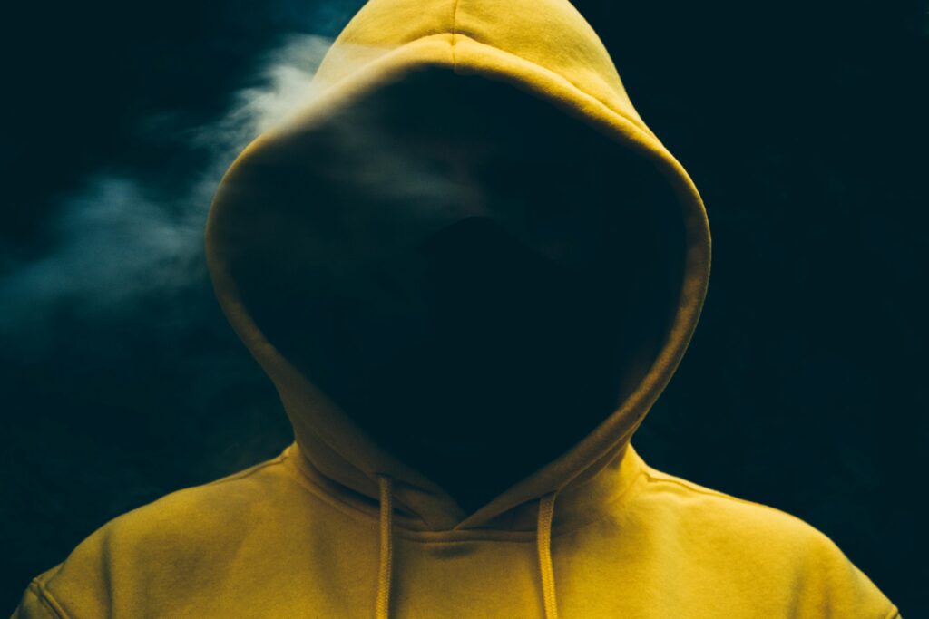 Brian Begin Person wearing a yellow hooded sweatshirt with their face obscured by shadows and some smoke in the background. Brian Begin Podcast