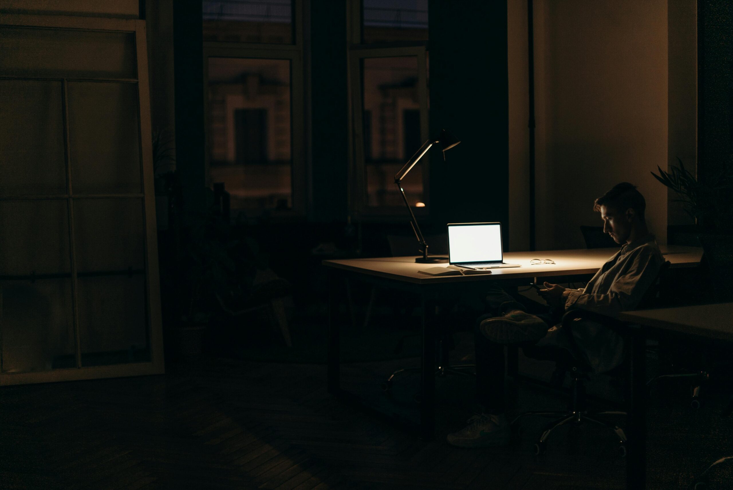 Brian Begin A person sits alone at a desk with a lit laptop in a dimly lit office at night. Brian Begin Podcast