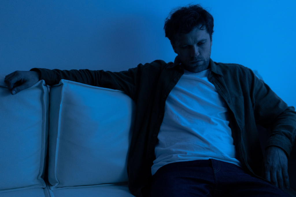 "Man sitting alone looking exhausted and disconnected, representing emotional numbness and being trapped in overthinking"