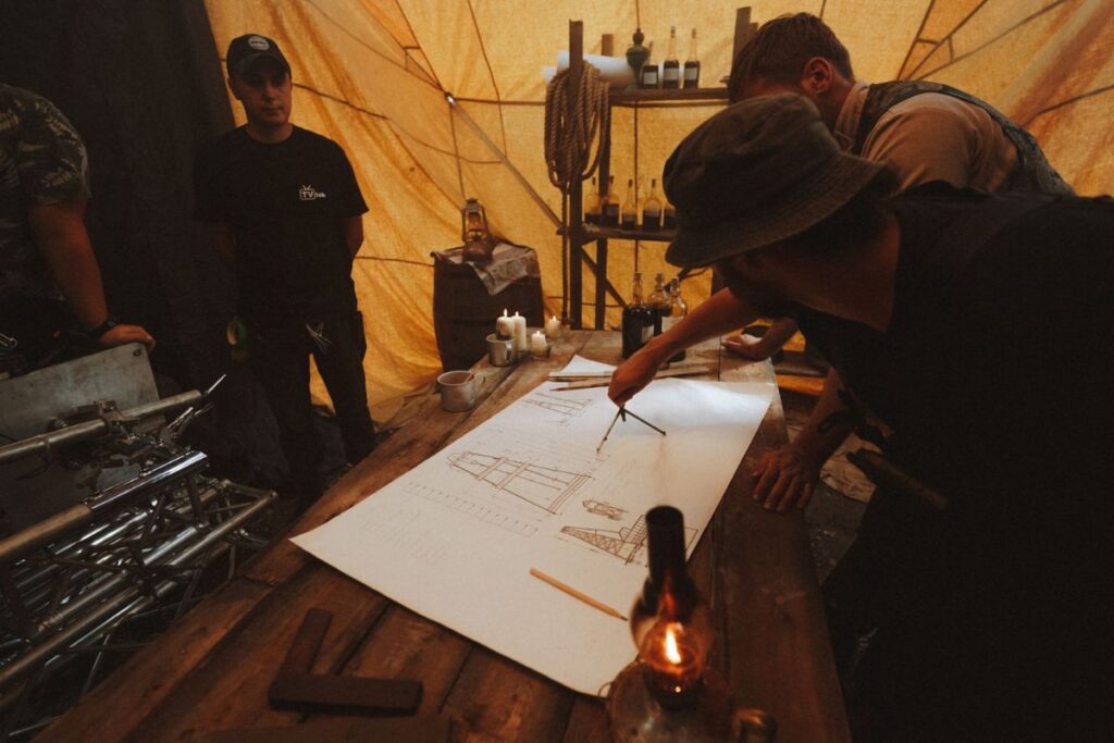 "Architects gathered around building blueprints representing collective visualization and the energetic field at work before physical creation"