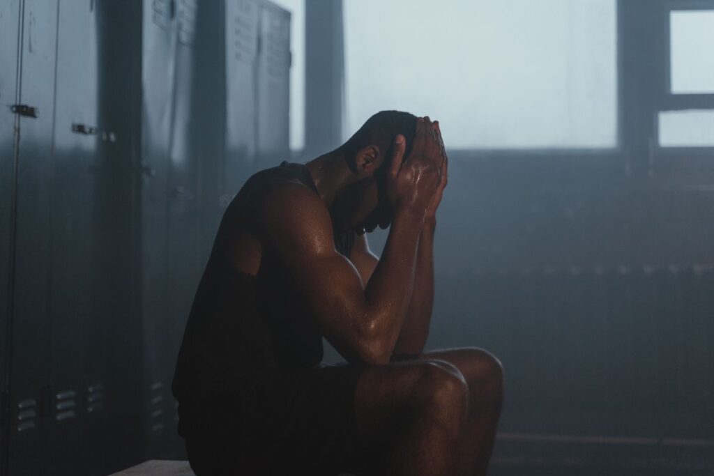 "Person looking exhausted and emotionally drained, representing the burnout and apathy phase of the push-crash-recovery cycle"