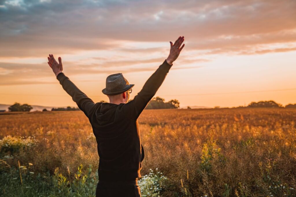 "Person standing relaxed and open in a wide landscape representing the energetic state of allowing, receiving, and field expansion"